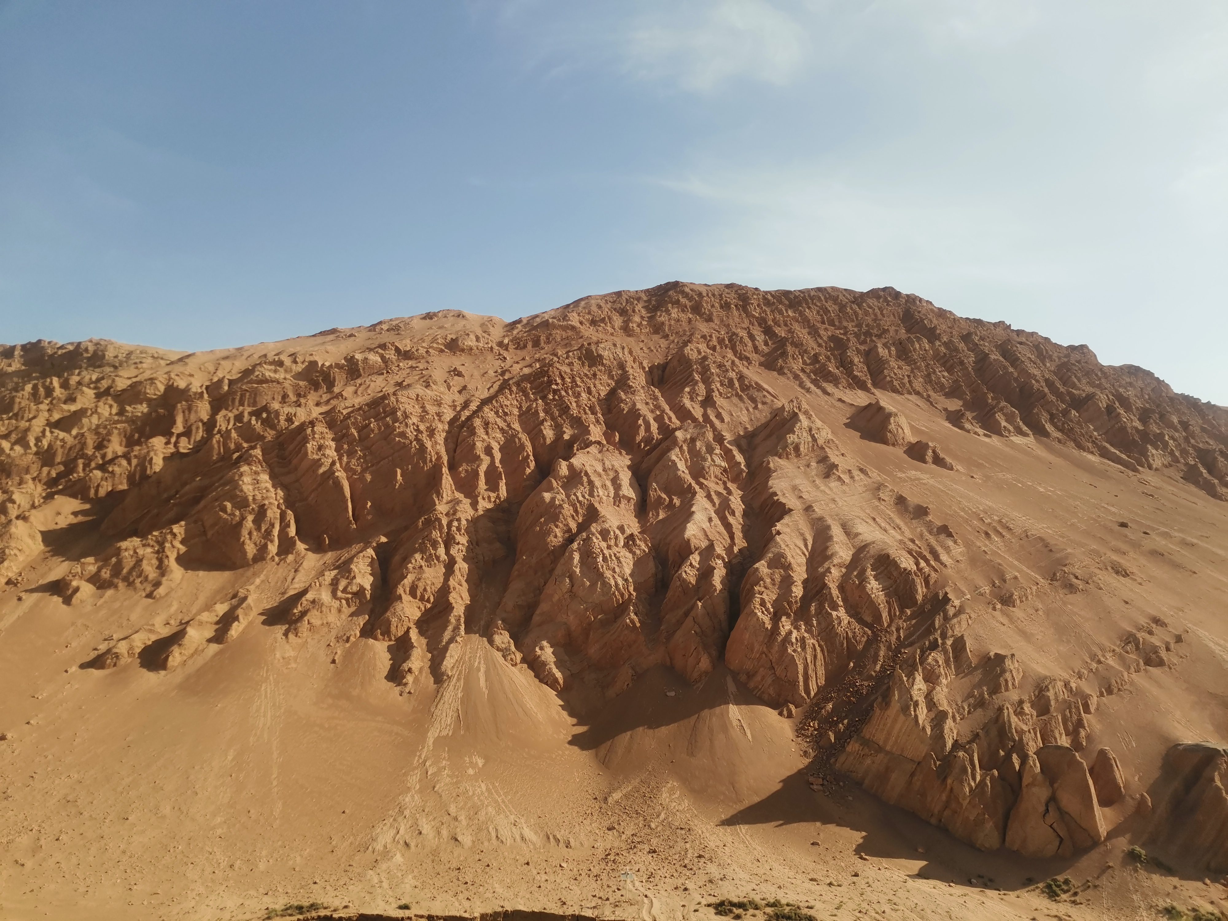 Rugged reddish-brown slopes of the Flaming Mountains under a clear blue sky in Turpan, China.