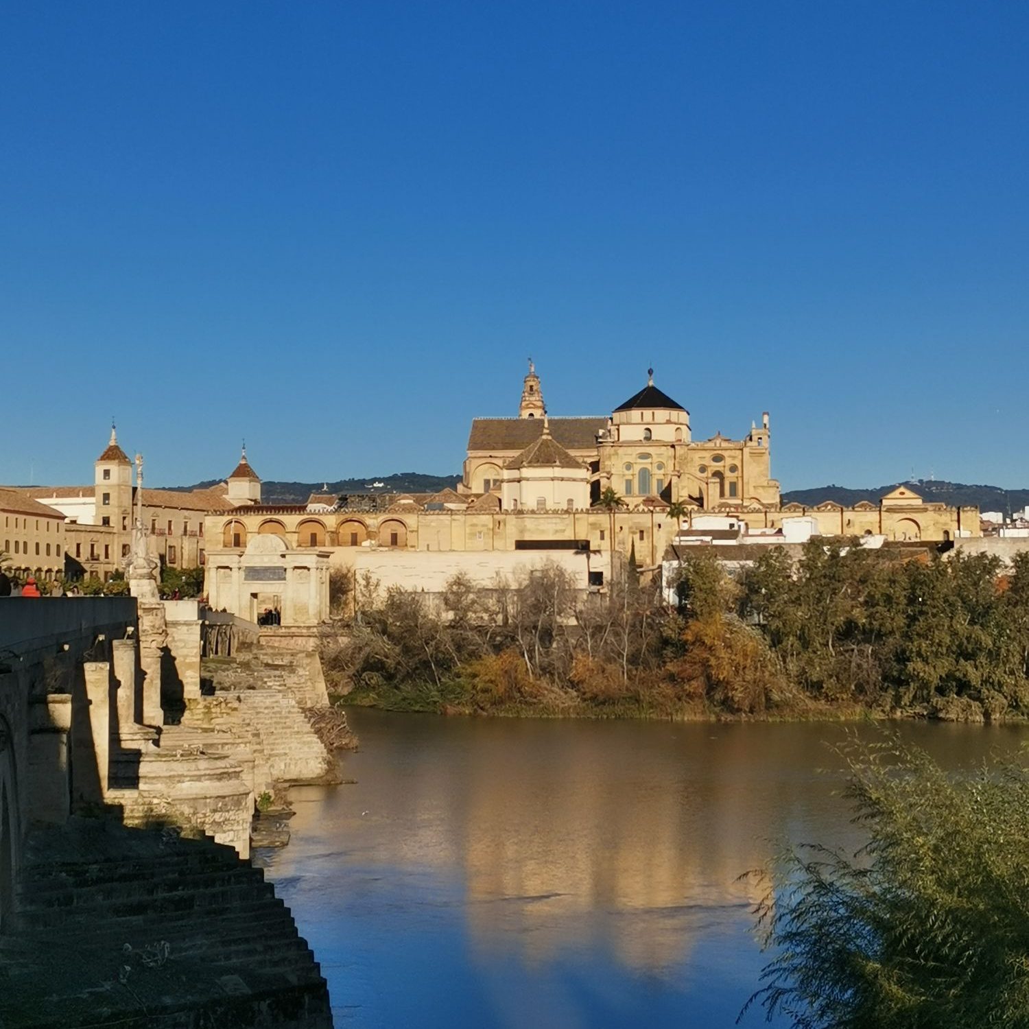 Panoramic view of the Cordoba skyline featuring the Mosque-Cathedral, the Roman Bridge, and the Guadalquivir River.